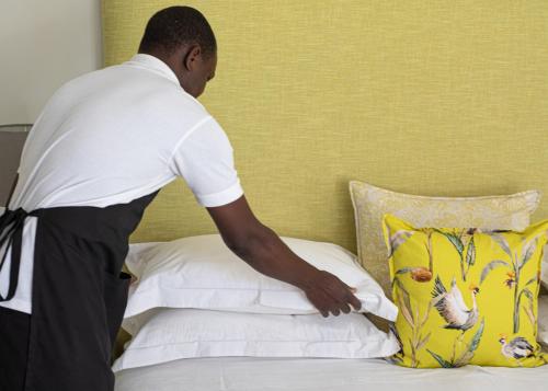 a man is putting sheets on a bed at The Parkwood in Johannesburg