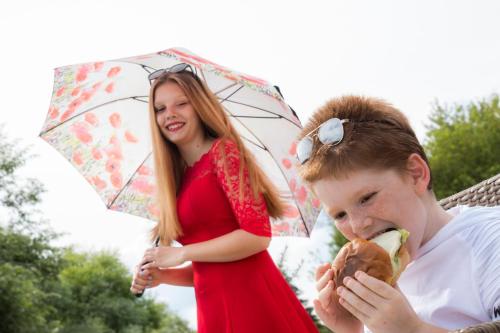 a young girl eating a hamburger and a woman holding an umbrella at Tó Wellness Hotel in Bánk