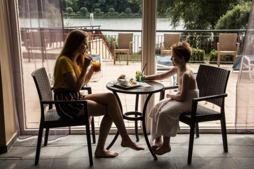 two women sitting at a table with a child at Tó Wellness Hotel in Bánk