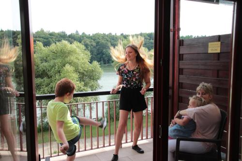 a woman standing on a balcony with a group of people at Tó Wellness Hotel in Bánk