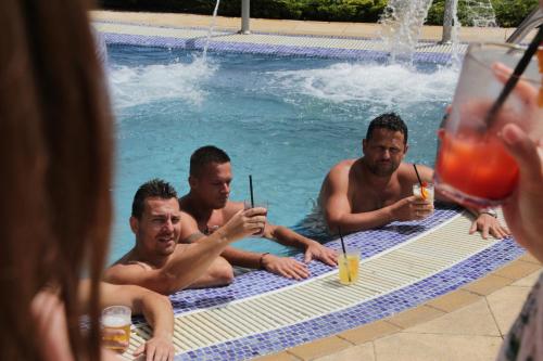 a group of men in a swimming pool with drinks at Tó Wellness Hotel in Bánk