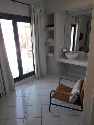 a bathroom with a sink and a chair and a mirror at Minois Boutique Hotel in Stalida