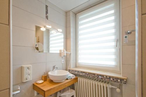 ein Bad mit einem Waschbecken, einem Spiegel und einem Fenster in der Unterkunft Hotel Harz in Hahnenklee-Bockswiese