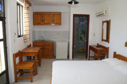 Cet appartement comprend une chambre avec un lit et une table ainsi qu'une cuisine. dans l'établissement Andavis Hotel, à Kardamaina