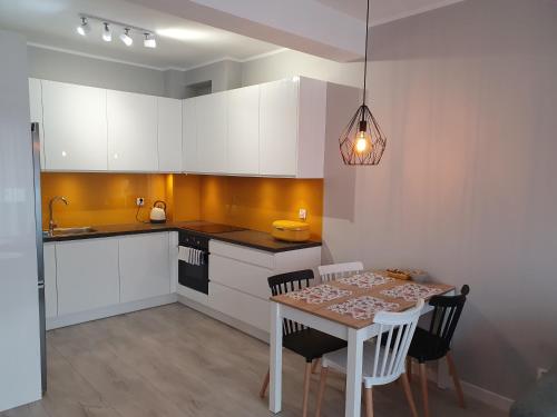 a kitchen with white cabinets and a table with chairs at Apartament Słoneczny Air Conditioning in Słupsk