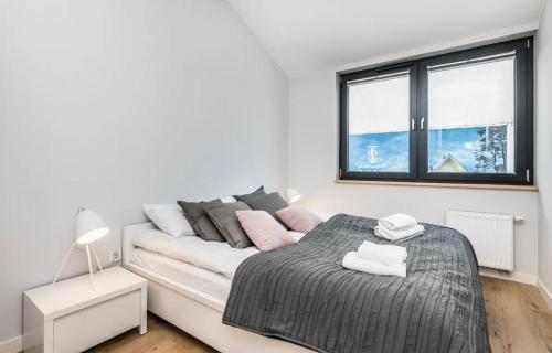 een witte slaapkamer met een bed en een raam bij Apartament Kołobrzeg in Kołobrzeg