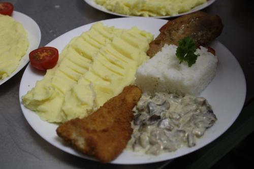 a plate of food with meat and potatoes and rice at Complex Turistic Dávid in Boghiş