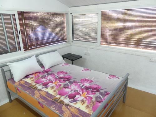 a bed with flowers on it in a room with windows at Aquamarine - Grand Baie - 4 chambres - Piscine in Grand-Baie