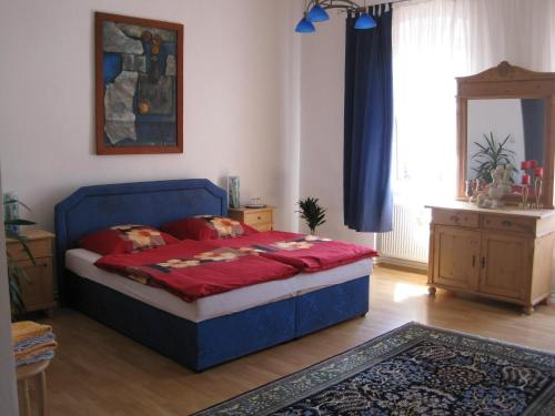 a bedroom with a blue bed with red pillows on it at Pension Phönix in Sighişoara