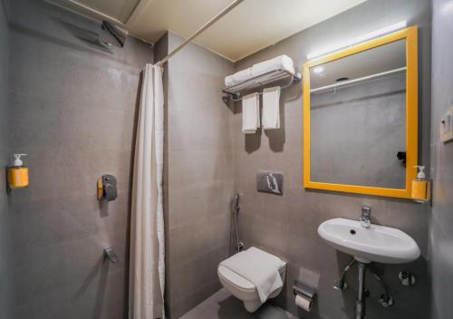 a bathroom with a sink and a toilet and a mirror at Bloom Hotel - Worli South Mumbai in Mumbai