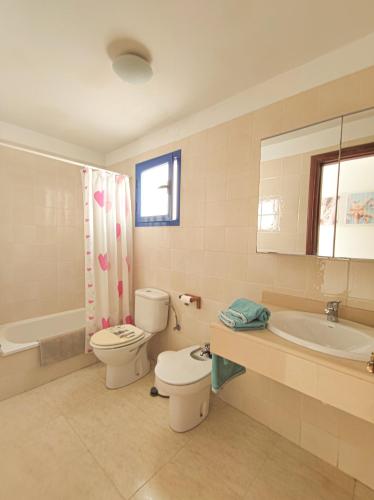 a bathroom with a toilet and a tub and a sink at VolKKanrentals Casa Machín in Famara
