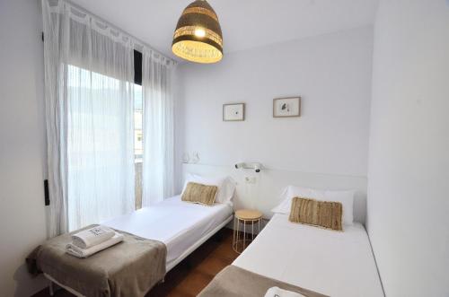 a white room with two beds and a window at Apartaments la Rambla - L'Arrel - 4 persones in Cornudella
