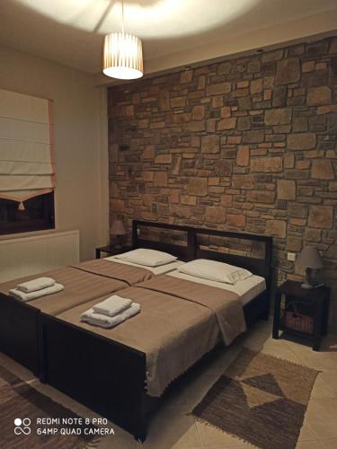 1 dormitorio con cama y pared de ladrillo en Evenos en Kato Loutraki