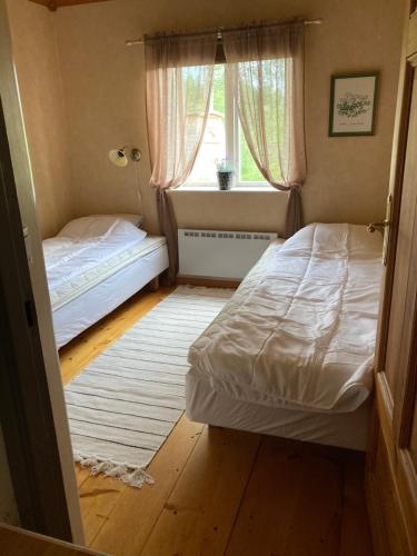 2 camas en una habitación pequeña con ventana en Trevlig stuga med endast 300 m till Dalälven., en Rudö