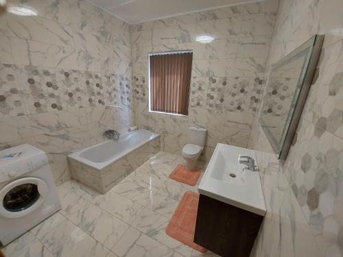 a bathroom with a sink and a washing machine at Trilogy, Ample Penthouse, Gozo in Kerċem