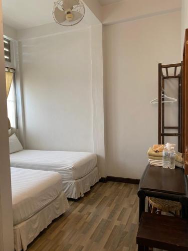 a bedroom with two beds and a table and a fan at Lamphuhouse Bangkok in Bangkok