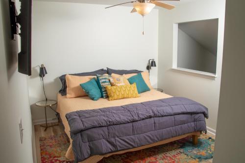 a bedroom with a bed with colorful pillows on it at True North - A Beach & Boat Lover's Dream in Carolina Beach