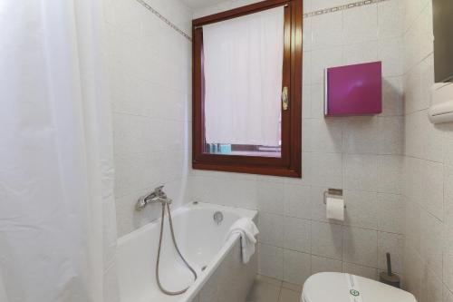 a bathroom with a tub and a toilet and a window at Wonderful studio Wi-Fi AC in Venice