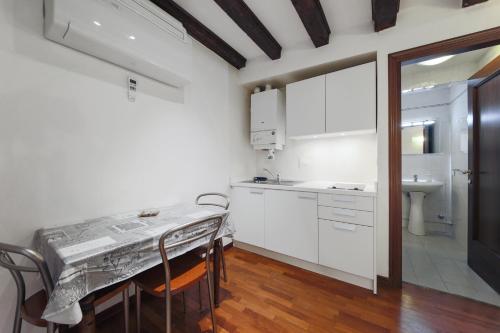 ヴェネツィアにあるWonderful studio Wi-Fi ACの白いキャビネット、テーブルと椅子付きのキッチンが備わります。