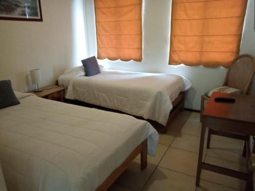 Habitación con 2 camas, mesa y escritorio. en Apart Hotel Sendero del Sol, en La Serena