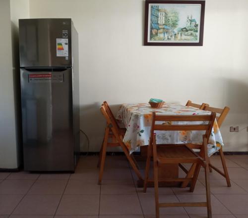 a kitchen with a table and a refrigerator at Apart Hotel Sendero del Sol in La Serena