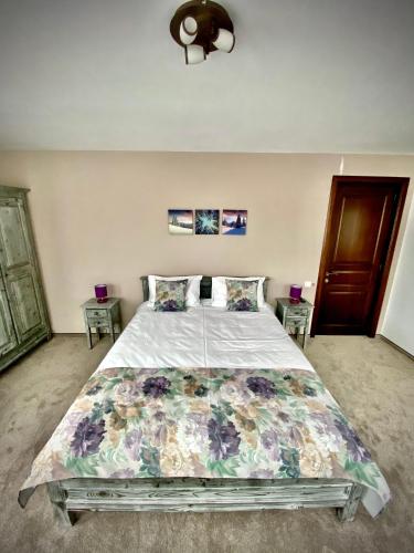 a bedroom with a large bed with a floral bedspread at CASA ANKELI in Buşteni