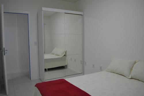 biała sypialnia z lustrem i łóżkiem w obiekcie Apartamento Praia do Santinho w mieście Florianópolis