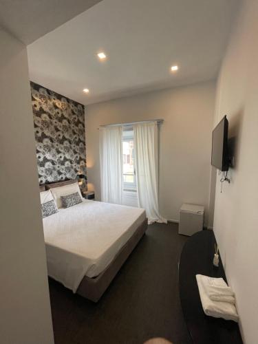 a bedroom with a bed and a television and a window at Villino Saraceno Rostain in Borgio Verezzi