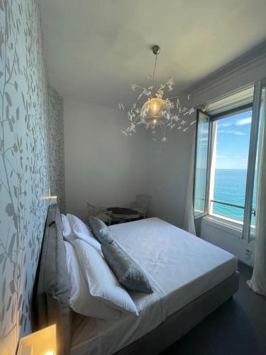 a bedroom with a bed with a chandelier and a window at Villino Saraceno Rostain in Borgio Verezzi