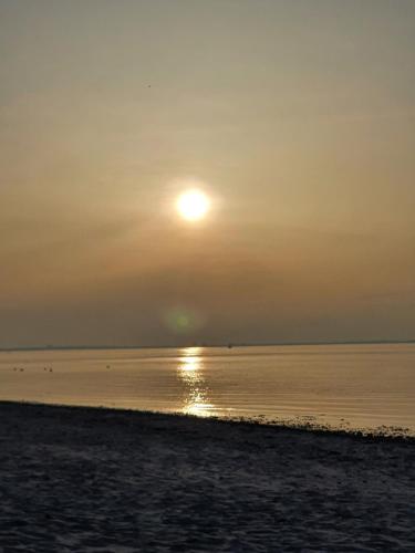 a sun setting over the water on a beach at Hamburg Niendorf-Suite in Hamburg