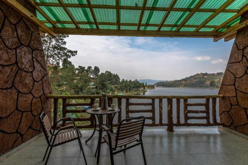 a table and chairs on a balcony with a view of a lake at Bunyonyi Overland Resort in Kabale