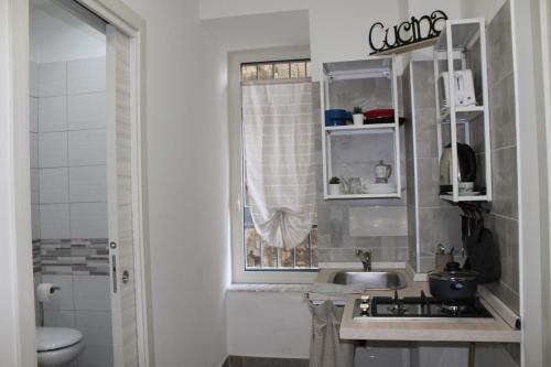 ein kleines Bad mit einem Waschbecken und einem Fenster in der Unterkunft riccia, frolla e babbà in Neapel