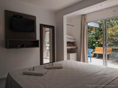 a bedroom with a bed and a mirror and a window at Vila Alaide Praia Hotel in Barra Velha