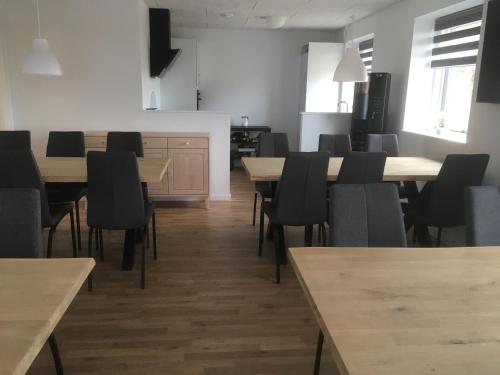 a dining room with wooden tables and black chairs at Fælleshuset Kirkebakken in Otterup