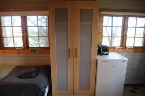a bedroom with two windows and a bed and a refrigerator at Skógarkot Cottage in Selfoss