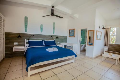 a bedroom with a blue bed and a bathroom at Treetops Hotel in Caye Caulker