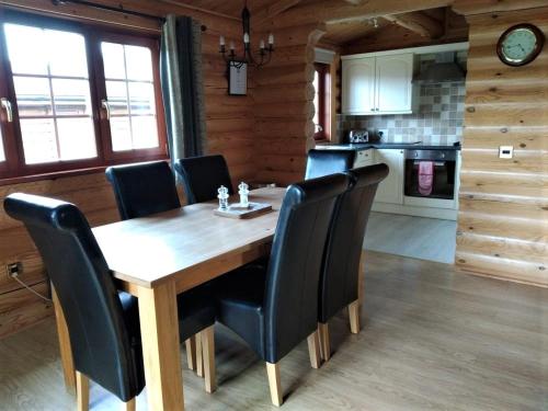 uma mesa de madeira com cadeiras pretas numa cozinha em Osiers Country Lodges em Diss