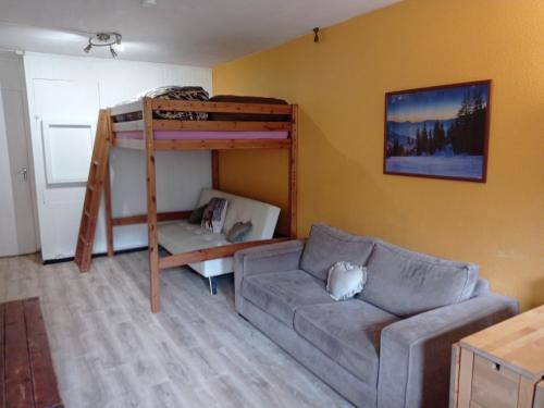 uma sala de estar com um sofá e um beliche em STUDIO en PLEINE MONTAGNE AVEC VUE SUR MARMOTTES em La Mongie