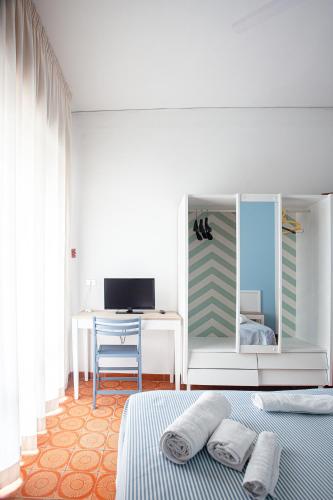 a bedroom with a bed and a desk with a mirror at Piccolo Hotel Kursaal in Cesenatico