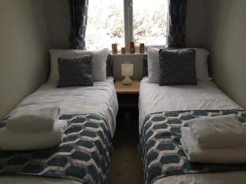 twee bedden in een kamer met een raam bij The Southwick lodge in Morpeth