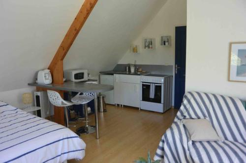 ein Zimmer mit einem Bett, einem Tisch und einer Küche in der Unterkunft Studio meublé près des plages du débarquement in Émiéville
