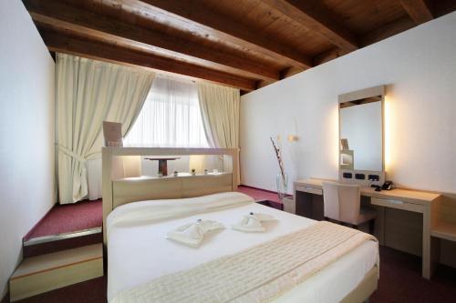 a bedroom with a large white bed and a desk at Cocca Hotel Royal Thai Spa in Sarnico
