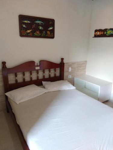una camera da letto con un grande letto bianco con testiera in legno di Ubatuba Suites Itamambuca a Ubatuba
