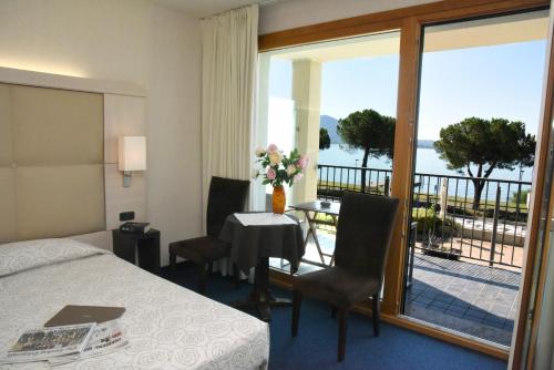 a hotel room with a bed and a table and a balcony at Cocca Hotel Royal Thai Spa in Sarnico