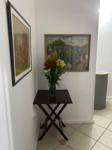 a vase of flowers on a table next to a painting at Ipanema Club Hostel in Rio de Janeiro