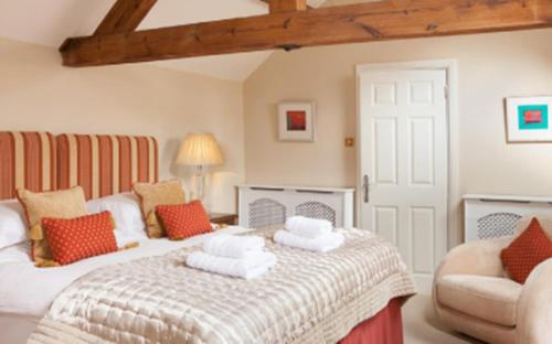 a bedroom with a large bed and a chair at The Old Kiln House in Shipston on Stour