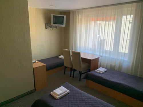 a hotel room with two beds and a table with chairs at Laisves 30 in Mažeikiai