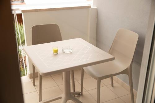 a white table with two chairs and a glass of orange juice at Marigold Residence in Roseto degli Abruzzi