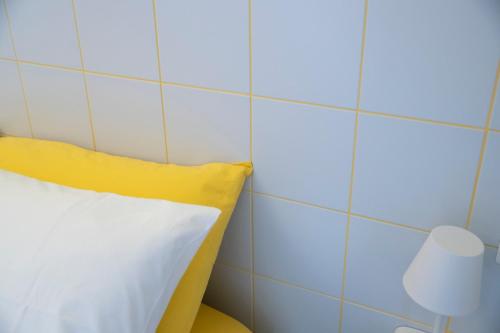 uma almofada amarela e branca num quarto com uma parede em azulejo em Marigold Residence em Roseto degli Abruzzi
