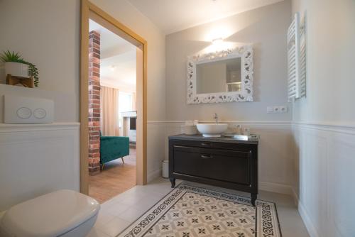 a bathroom with a sink and a toilet and a mirror at Apartamenty Rynek 27 in Prószków